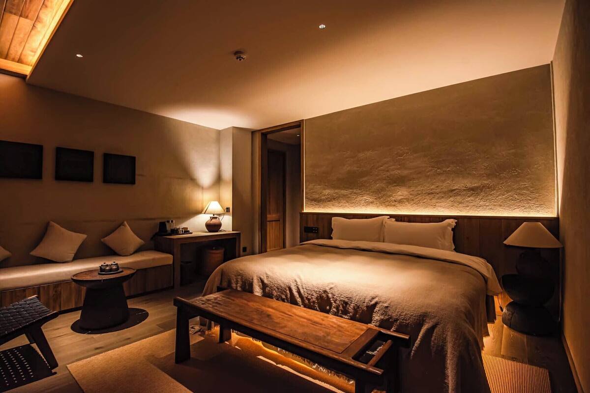 Una habitación de hotel moderna con una cama grande, un sofá, una mesita y un escritorio con un teclado.