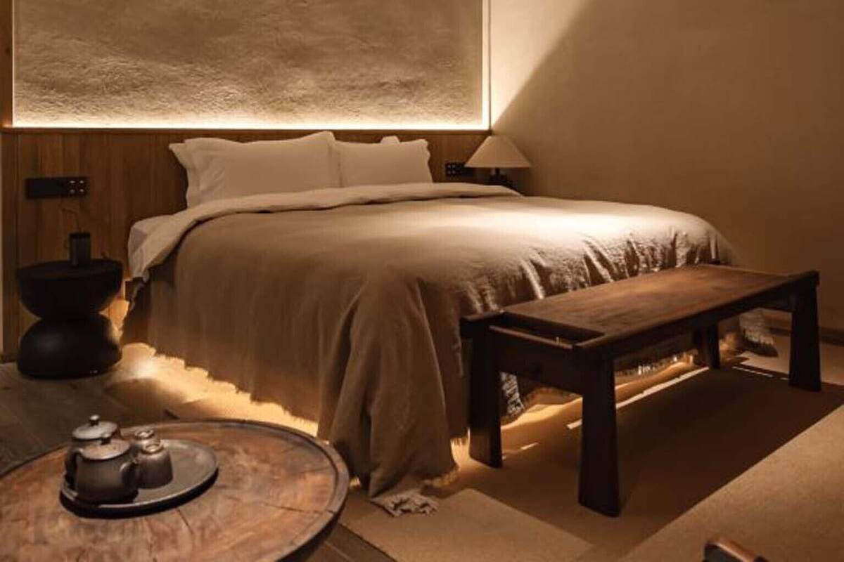 Un dormitorio moderno con una cama grande, una mesita de noche y una mesa redonda con una tetera.