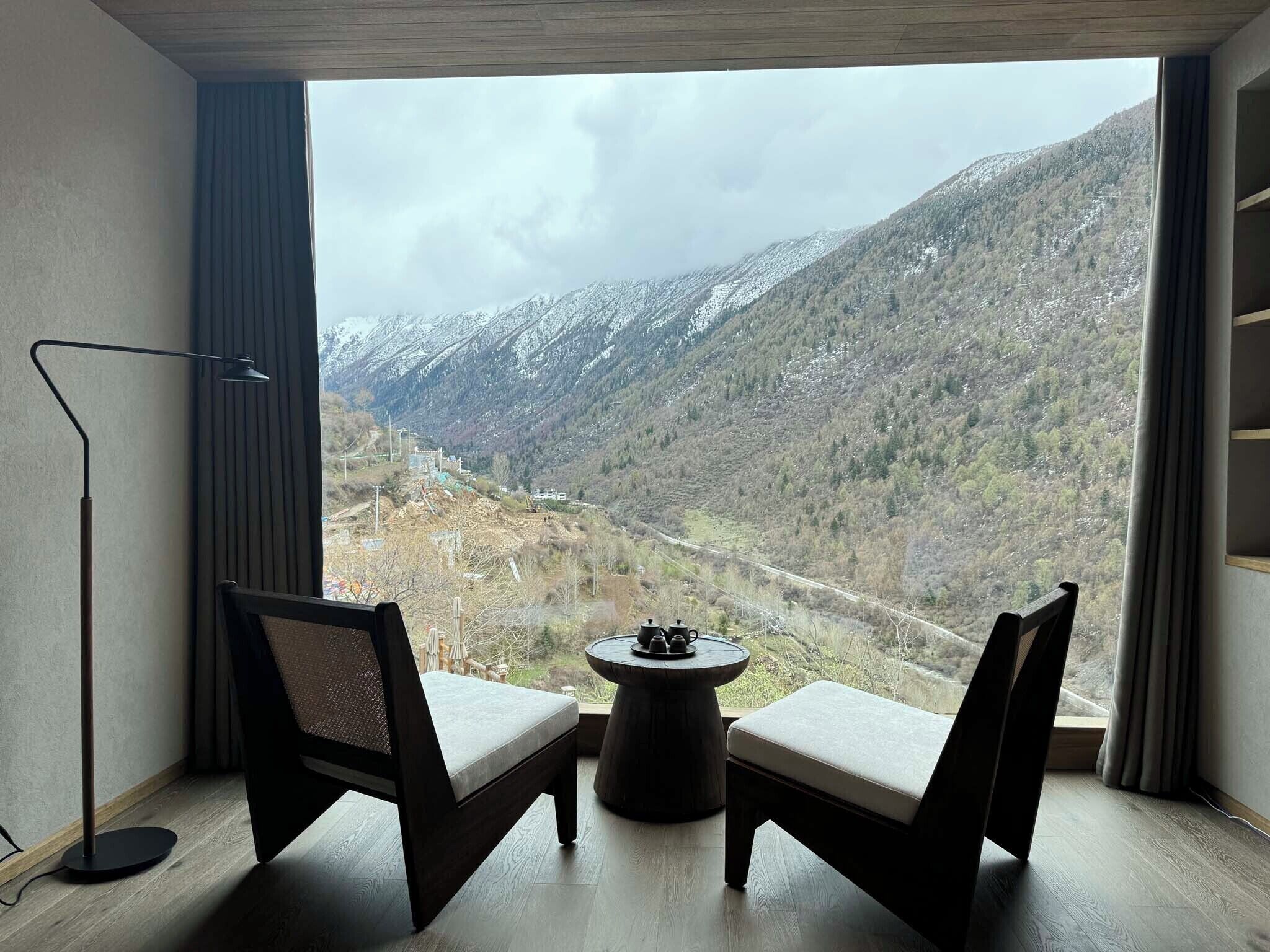 A room with two chairs facing a large window overlooking a mountainous landscape.