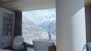 A modern bathroom with a large bathtub, a white chair, and a small table.