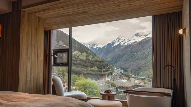 A bedroom with a large window offering a mountain view.