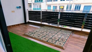 A balcony with a wooden floor, a green artificial grass area, and a patterned mat. - Johor Senai (Senai)