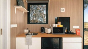 Een kleine keuken met een spoelbak, magnetron, broodrooster en een kleine koelkast.