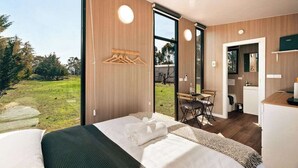 Een moderne slaapkamer met een groot bed, een bureau en uitzicht op het omliggende landschap.