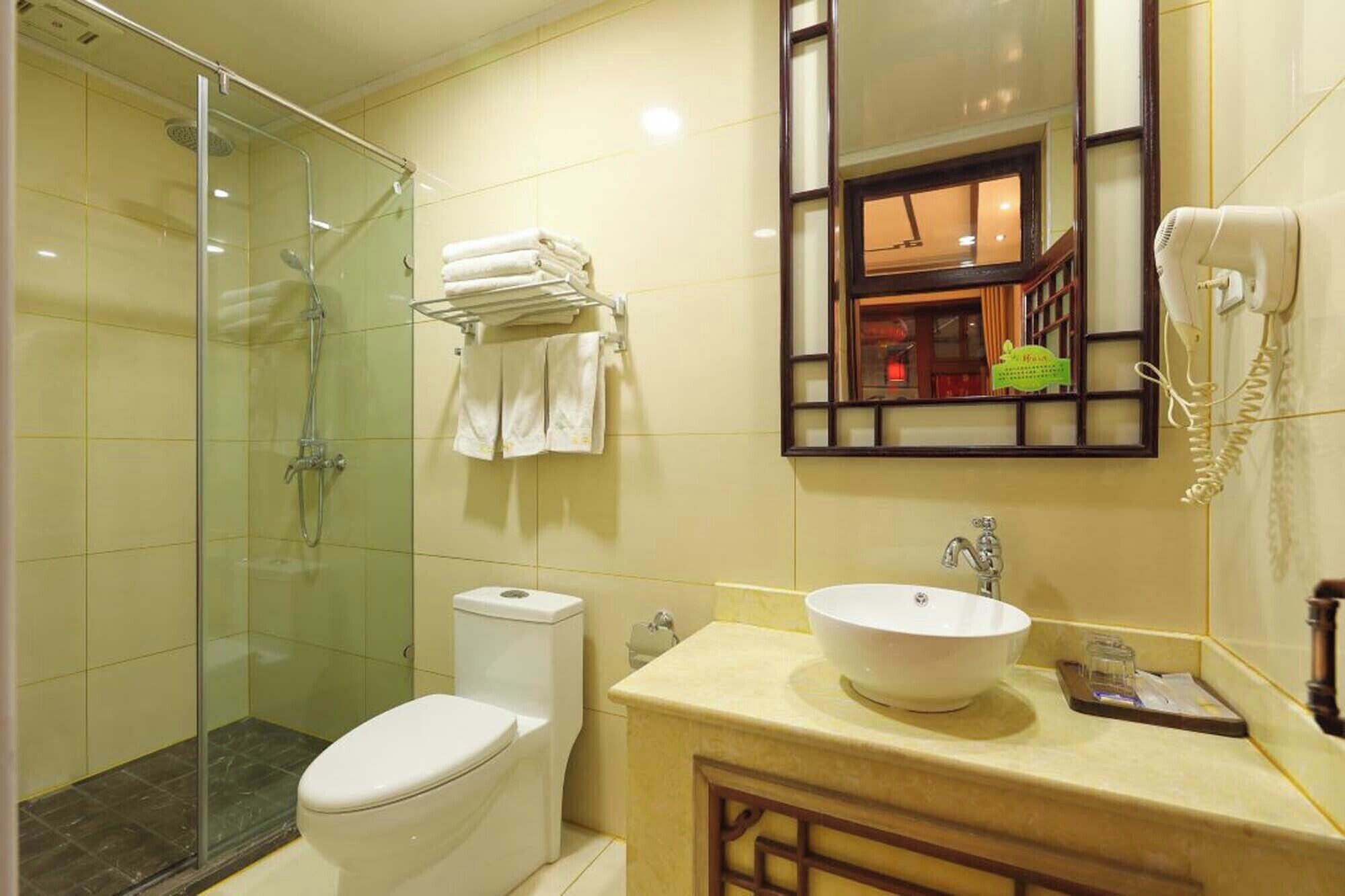 Une salle de bain avec une douche à parois de verre, des toilettes, un lavabo avec un miroir au-dessus et un téléphone fixé au mur.