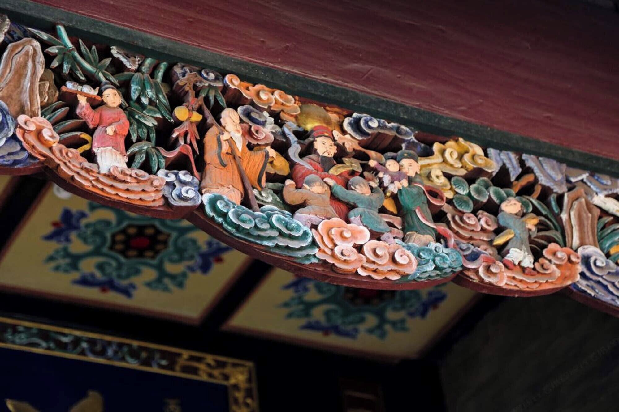 Eine detailreiche Decke mit aufwendigen Schnitzereien und Figuren, vermutlich Teil der Architektur eines traditionellen oder historischen Gebäudes.