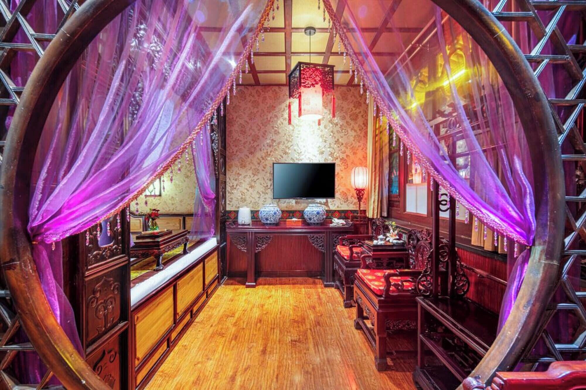 Una habitación tradicional con televisión, muebles de madera y un papel tapiz estampado.