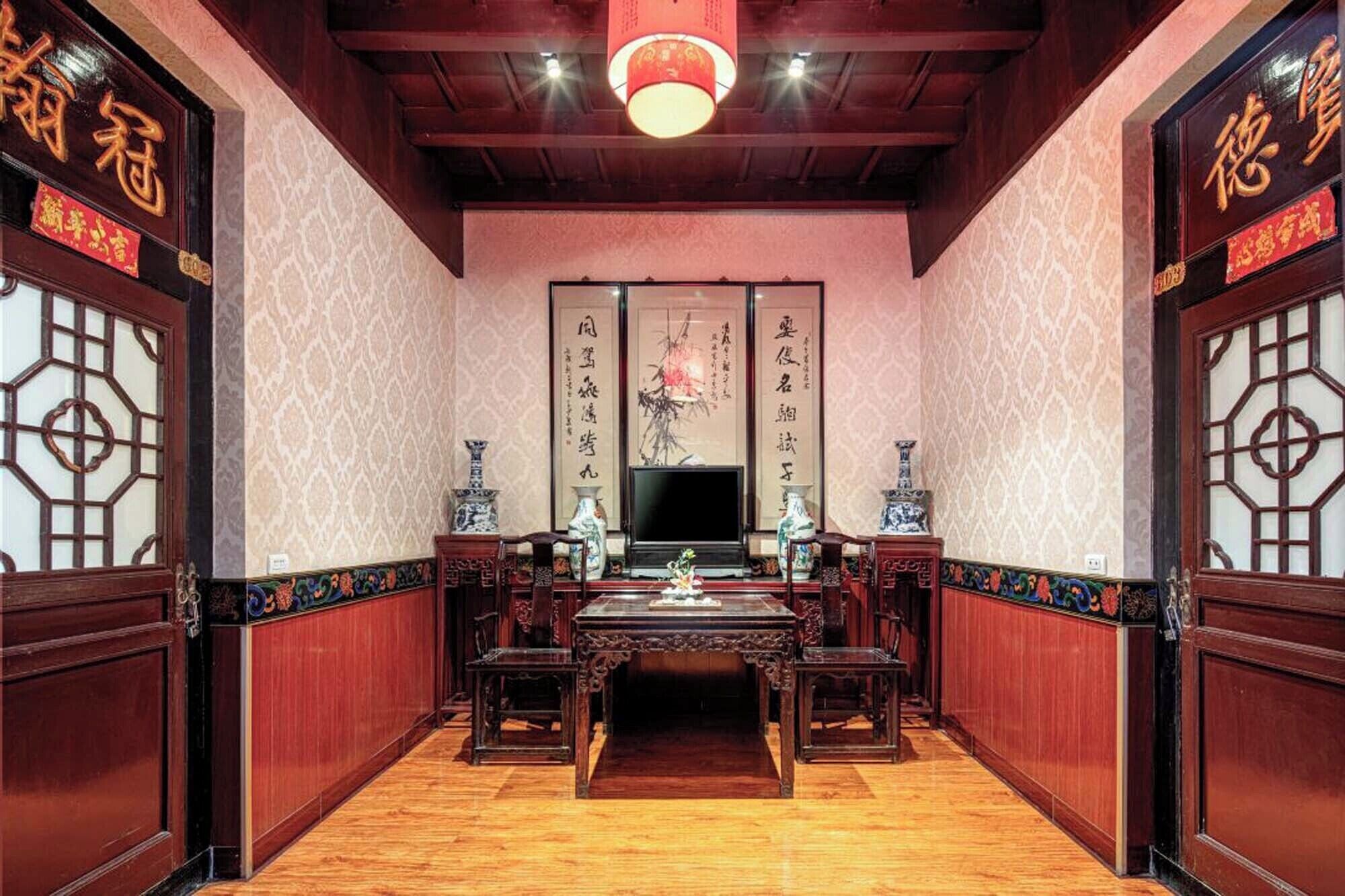 Ein traditioneller chinesischer Raum mit Holzmöbeln, einem Fernseher und Kalligraphie an den Wänden.