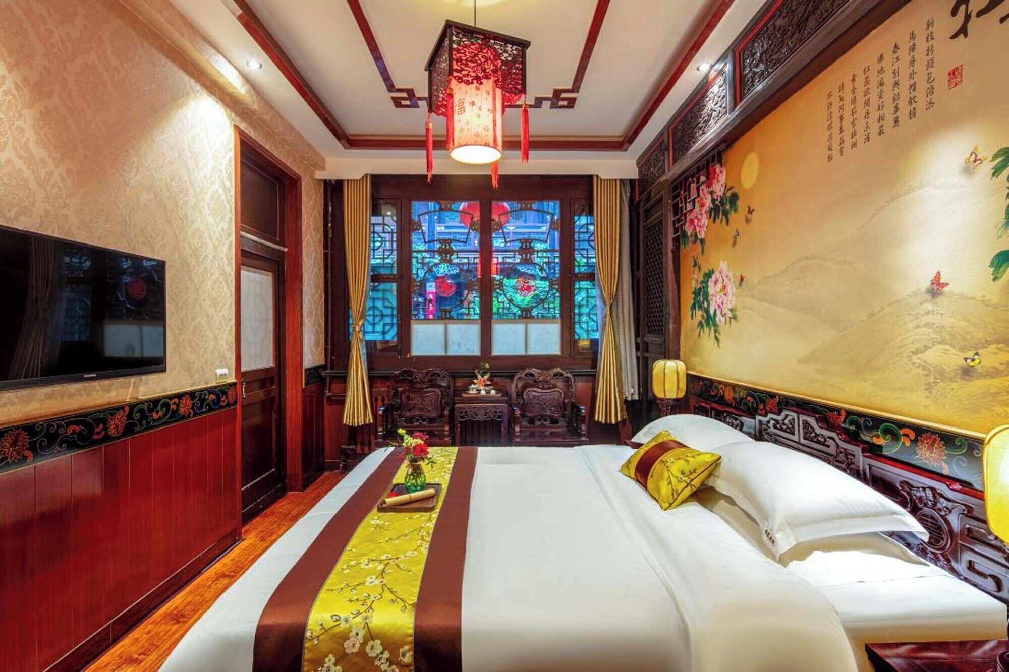 A traditional room with a bed, a television, a window with stained glass, and a wall with calligraphy.