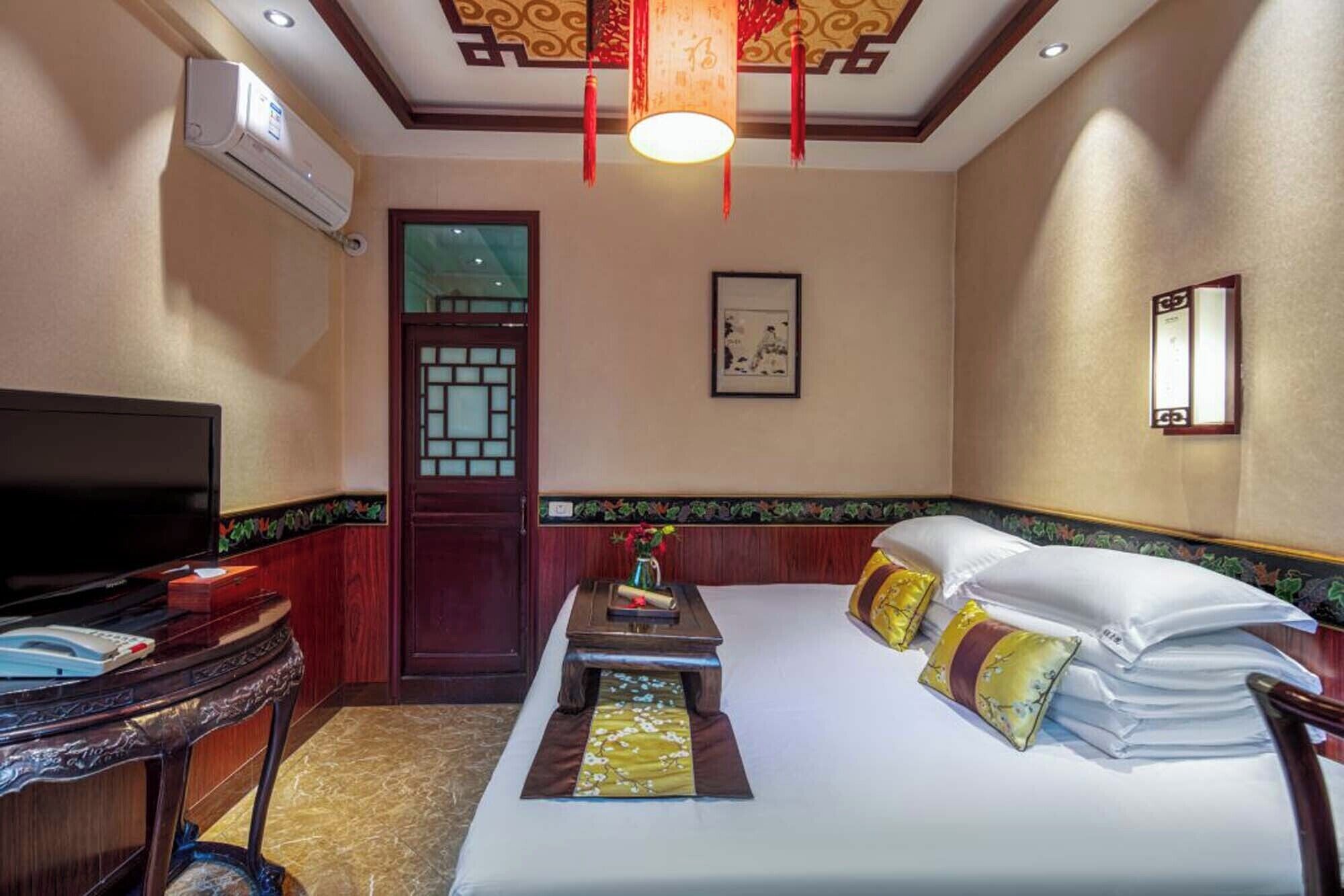 A hotel room with a bed, a TV, a desk, and a window.