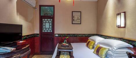 A hotel room with a bed, a TV, a desk, and a window.