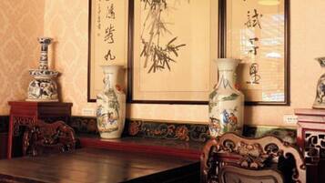 A traditional room with a wooden table and chairs, a vase, and calligraphy on the wall.