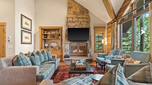 A cozy living room with a stone fireplace, a flat-screen TV, and comfortable seating.