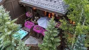 A house with a patio, a hot tub, and hanging flower baskets.