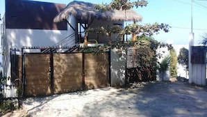 Une maison avec un toit de chaume, une entrée fermée par un portail et un petit jardin.