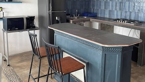Une cuisine moderne dotée d’un îlot central, de tabourets de bar, d’un ventilateur de plafond et d’un four à micro-ondes.