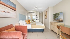 A hotel room with a bed, a desk, a chair, a TV, and a painting on the wall.