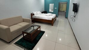 Une chambre d’hôtel moderne équipée d’un lit, d’un canapé, d’une table basse, d’un ventilateur de plafond et d’une télévision.