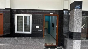 Un intérieur moderne avec un sol à carreaux, une fenêtre ornée d’une grille métallique et une porte donnant sur une autre pièce.