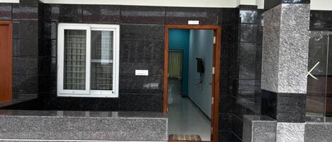 A modern interior with a checkered floor, a window with a metal grill, and a door leading to another room.