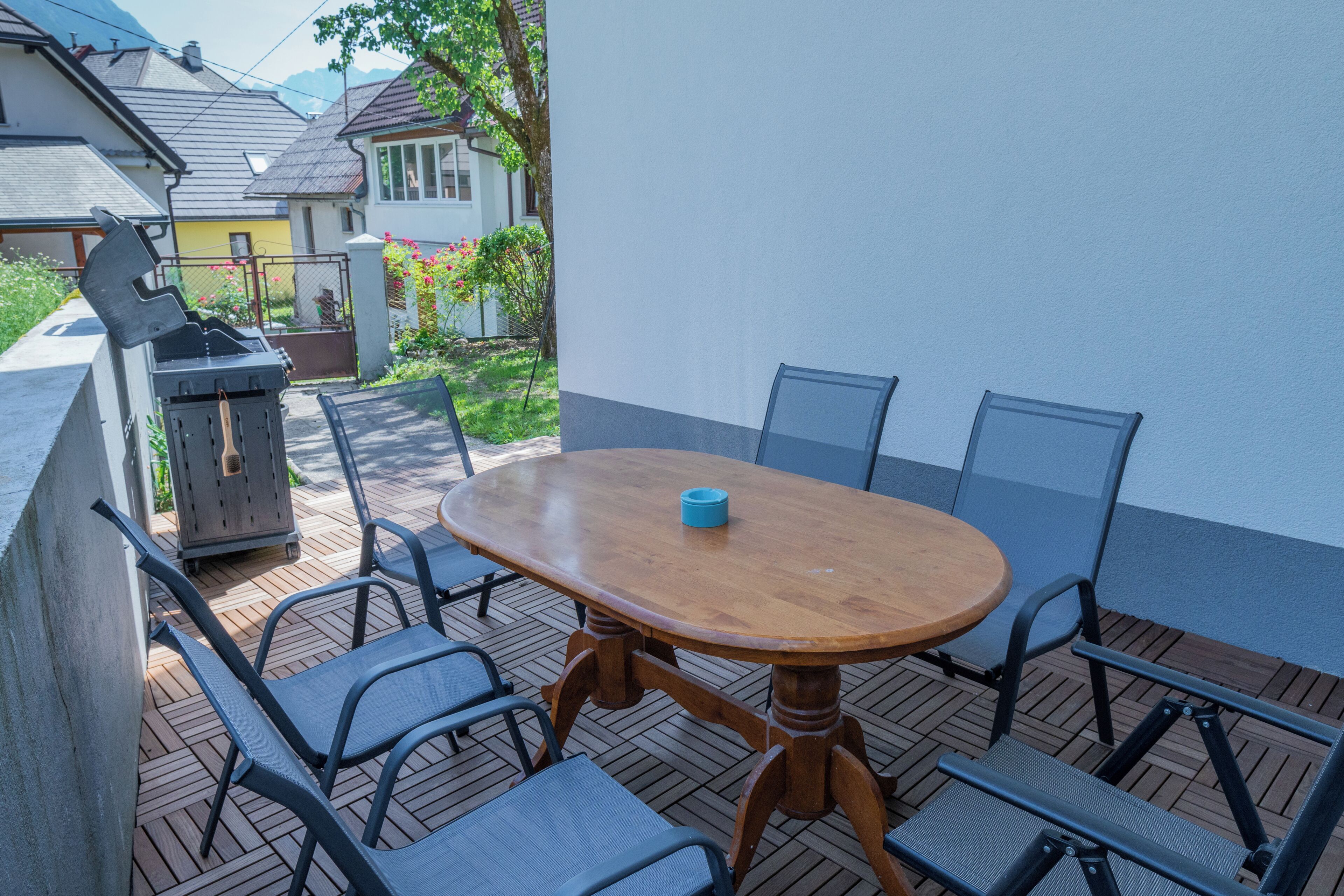 An outdoor patio with a wooden table and metal chairs.