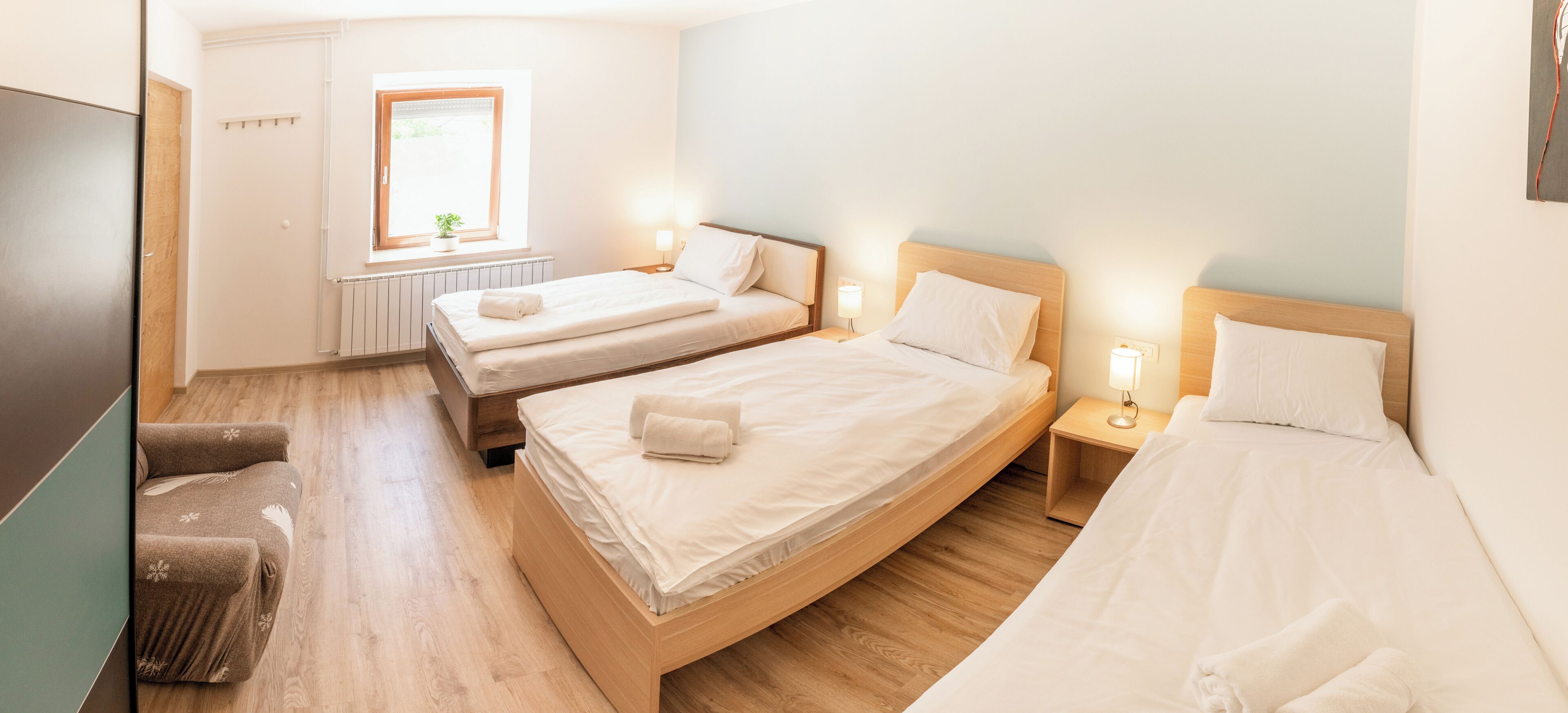 A hotel room with two beds, a small window, and bedside lamps.