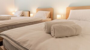 Ein Hotelzimmer mit zwei Betten, jeweils mit Kopfteil und Nachttischlampen.