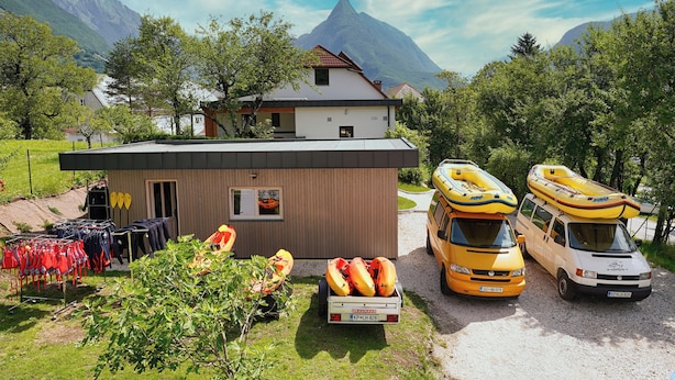 Eine Berglodge mit Kajaks und Rafts, ein kleines Gebäude und ein Van.