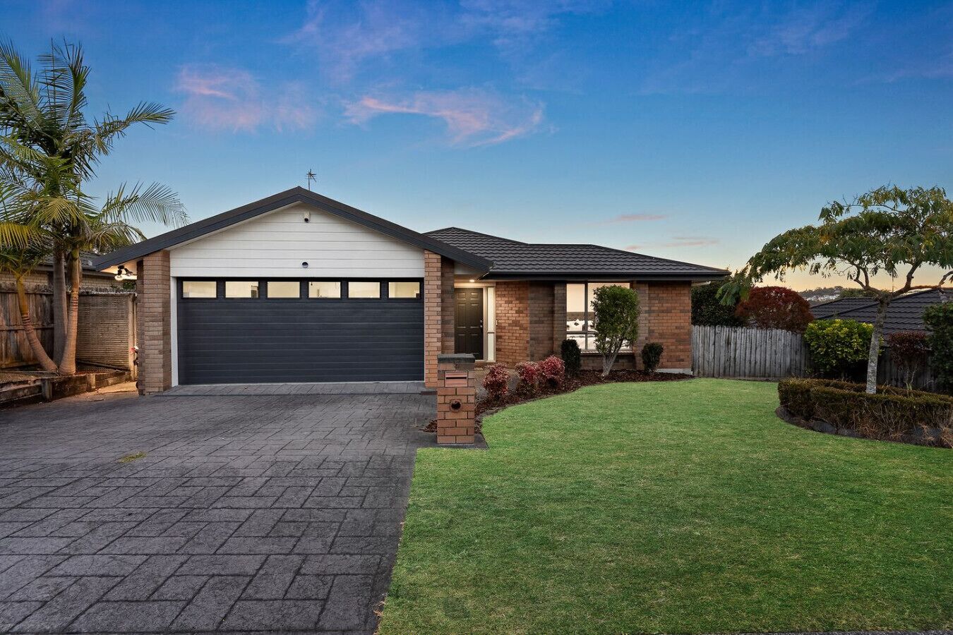 A residential house with a garage, a paved driveway, and a well-maintained lawn.
