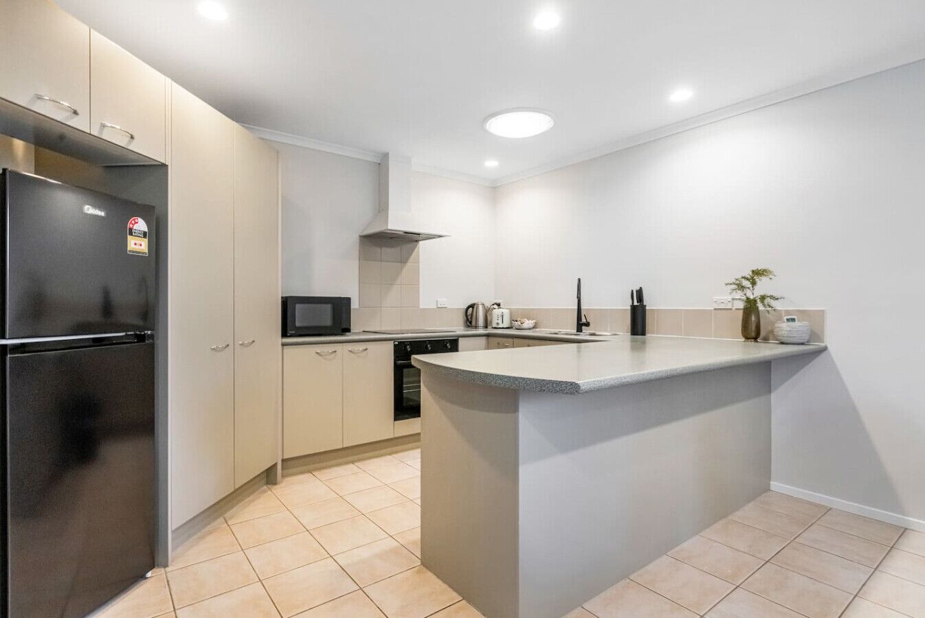 A modern kitchen with a built-in refrigerator, microwave, oven, and sink.