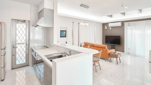 A modern kitchen with a central island, a dining area with a sofa, and a TV.