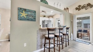 A kitchen with a bar area, white cabinets, and a decorative star sign on the wall.