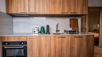 A modern kitchen with wooden cabinets, a built-in oven, a toaster, and a coffee machine.