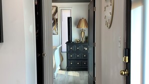 Un pasillo con un aparador de madera oscura, una lámpara y un reloj en la pared.