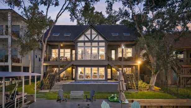 A two-story house with a large front porch, a swimming pool, and outdoor seating.