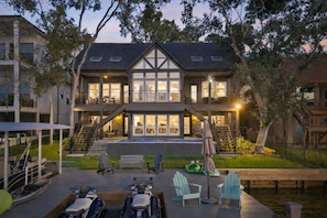 A two-story house with a large front porch, a swimming pool, and outdoor seating. - Luxury Lakefront: Gameroom, Pool, Spa, Amenities! Sleeps 16 - Family Friendly! (Montgomery)