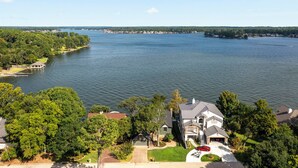 A residential area with houses near a large lake, featuring a prominent house with a garage and a driveway.