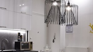 Eine moderne Küche mit weißen Schränken, einer Holztheke mit Barhocker, einer Edelstahl-Mikrowelle und Pendelleuchten.