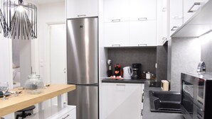 Eine moderne Küche mit weißen Schränken, einem Edelstahlkühlschrank, einer Kaffeemaschine und einer Mikrowelle.