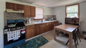 A kitchen with wooden cabinets, a stove, a microwave, and a window with blinds. - Fabulous 2-bedroom cottage in Wurtsboro (Wurtsboro)