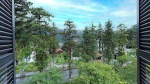 A view through a window of a residential area with trees, a road, and buildings. - Khach San Cong Doan Sapa (Sa Pa)
