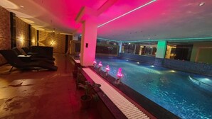 A swimming pool with a water feature, a seating area with chairs, and a brick wall. - HOTEL BELSSESHE (Bolpur)