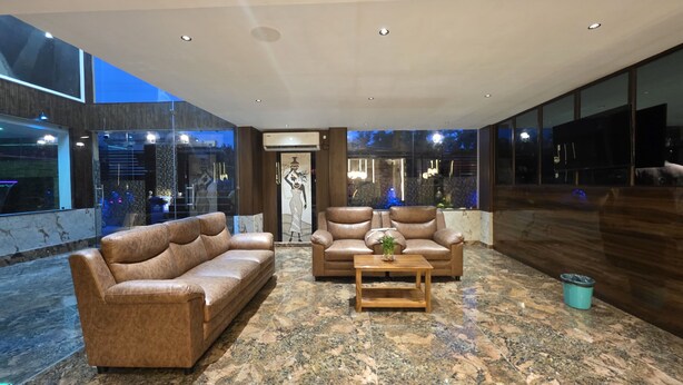 A modern living room with leather sofas, a wooden coffee table, and a marble floor. - HOTEL BELSSESHE (Bolpur)