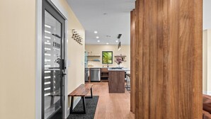 Una cocina moderna con una isla de madera, un comedor con un banco y una puerta de vidrio que da a otra habitación.