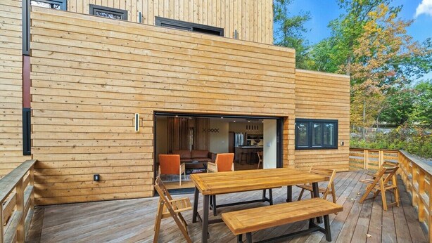 Una terraza de madera con zona de comedor, que incluye una mesa y bancos.