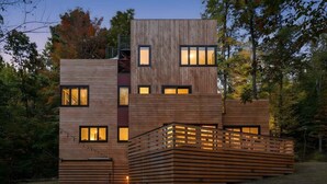 Un edificio moderno de varios pisos con fachada de madera, ventanas amplias y terraza de madera.