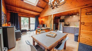 A cozy cabin interior with a dining area, kitchen, and a large window.