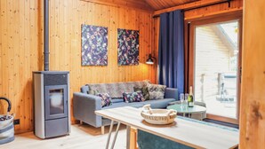 A cozy cabin interior with a wooden interior, a sofa, a table with a bowl, a bottle, and a lamp.