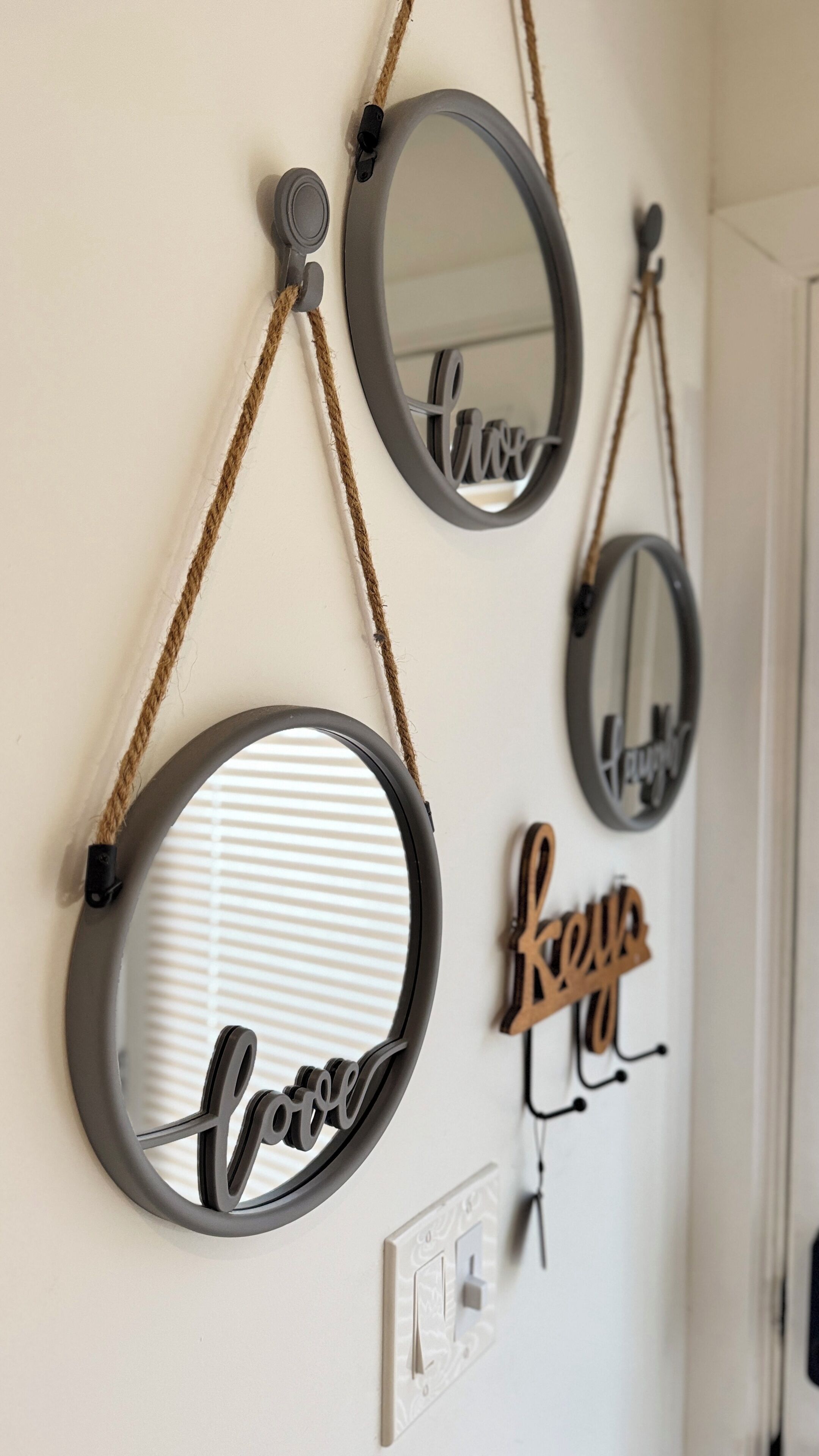 Three wall-mounted mirrors with ropes, each with a different word written inside.