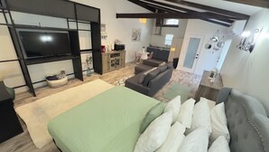 Un ambiente compatto con letto, divano e angolo cottura.